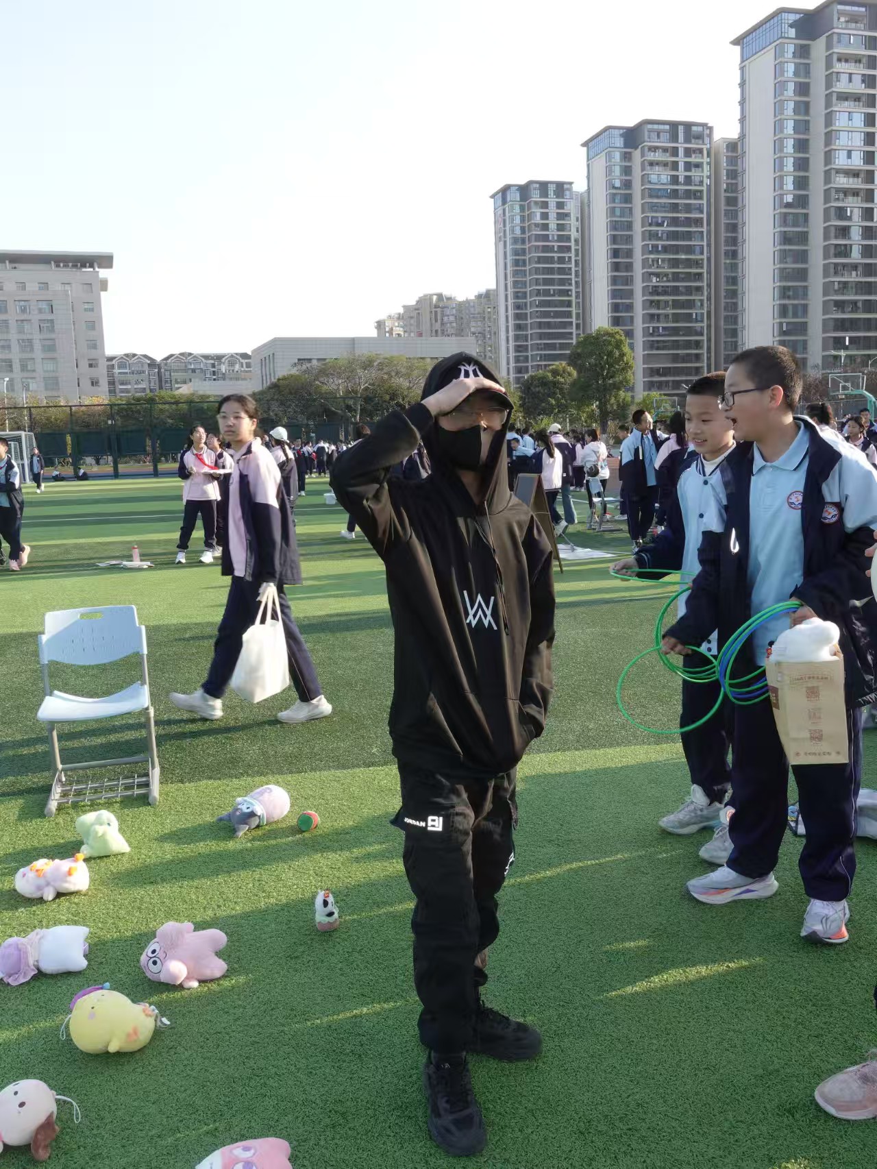 同学在摊位前玩套圈游戏，地上摆着玩偶奖品